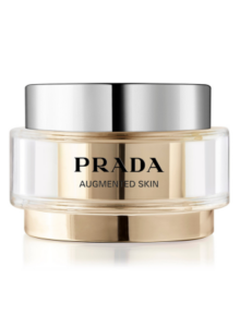 Beauty aus Italien: 2-in-1-Produkte wie die Tages und Nachpflege "Augmented Skin" in nur einem Produkt von Prada, die sich im goldfarbenen Tiegel mit großer Logoprägung in Schwarz und mit silbernem Deckel präsentiert.