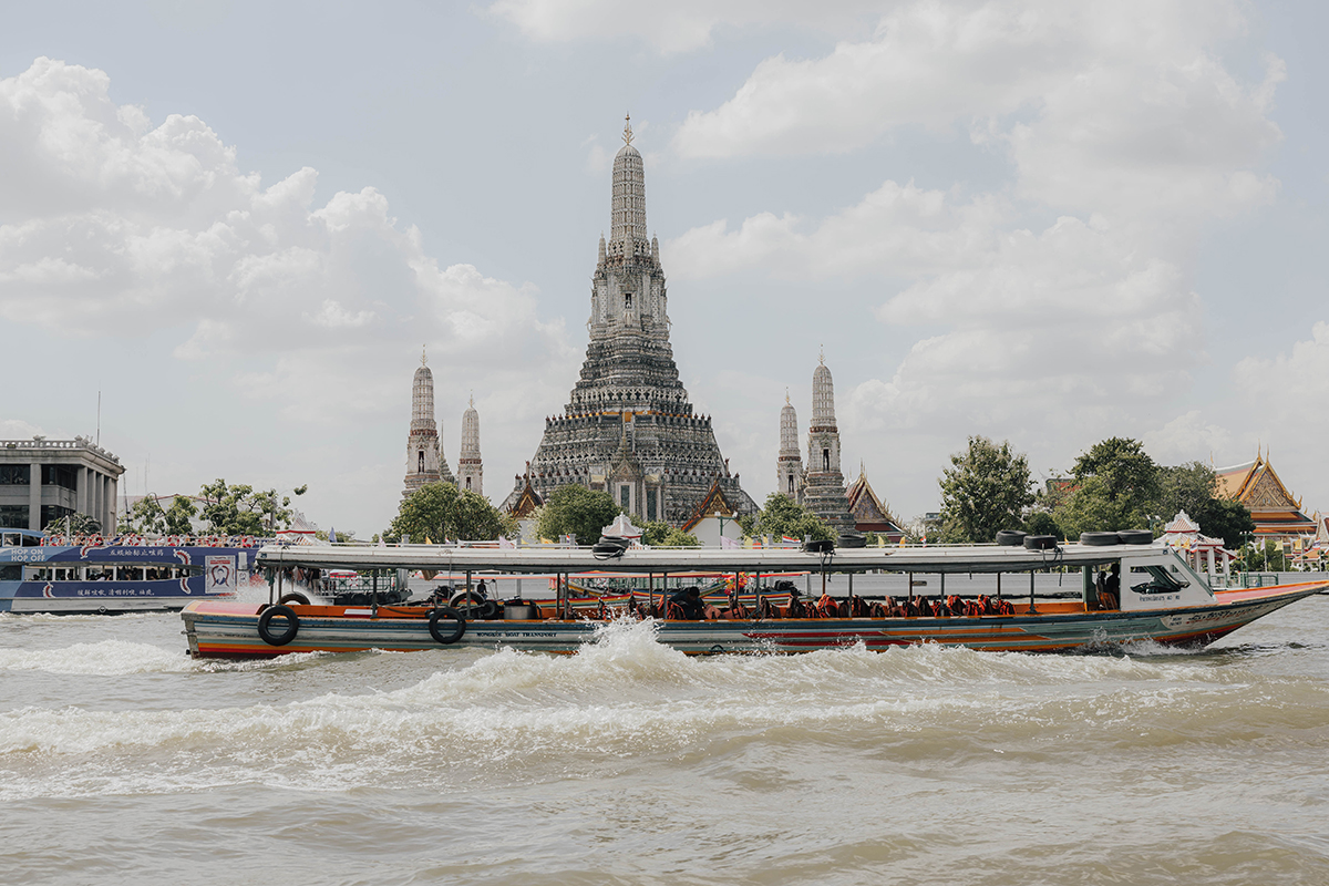 Ausflugsboot auf dem Fluss mit Wat Arun Tempel im Hintergrund