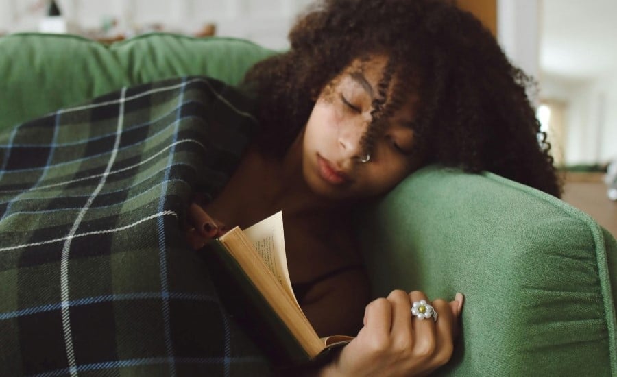 Frau liegt auf einem Sofa und liest ein Buch