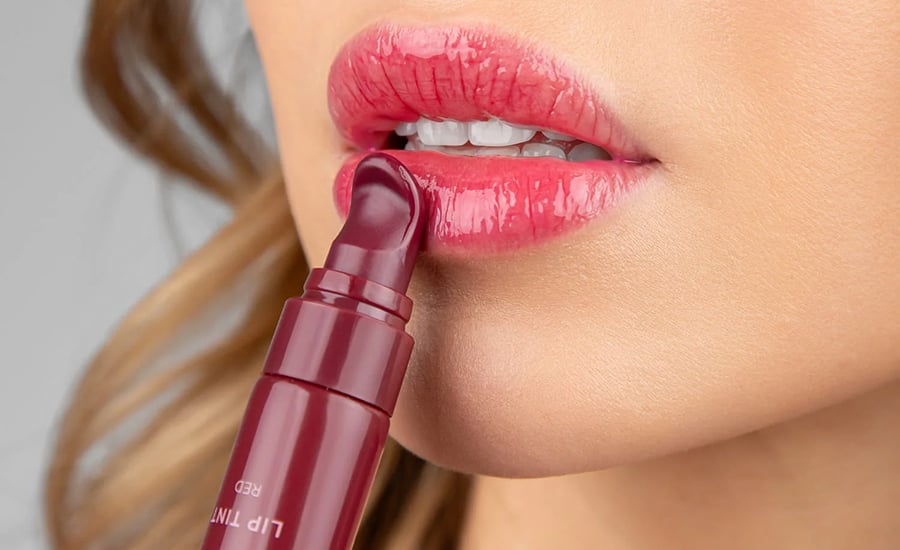 Nahaufnahme, wie ein Lip Tint in Rot direkt auf die Lippen aufgetragen wird, glänzendes Finish und sichtbare Lippenkonturen.