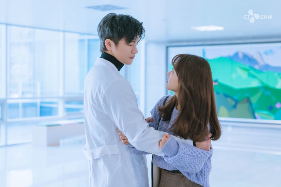 Szene aus dem K-Drama „Start-Up“: Ein Mann im weißen Arztkittel hält eine Frau in einem hellen Flur fest im Arm; beide wirken emotional angespannt.
