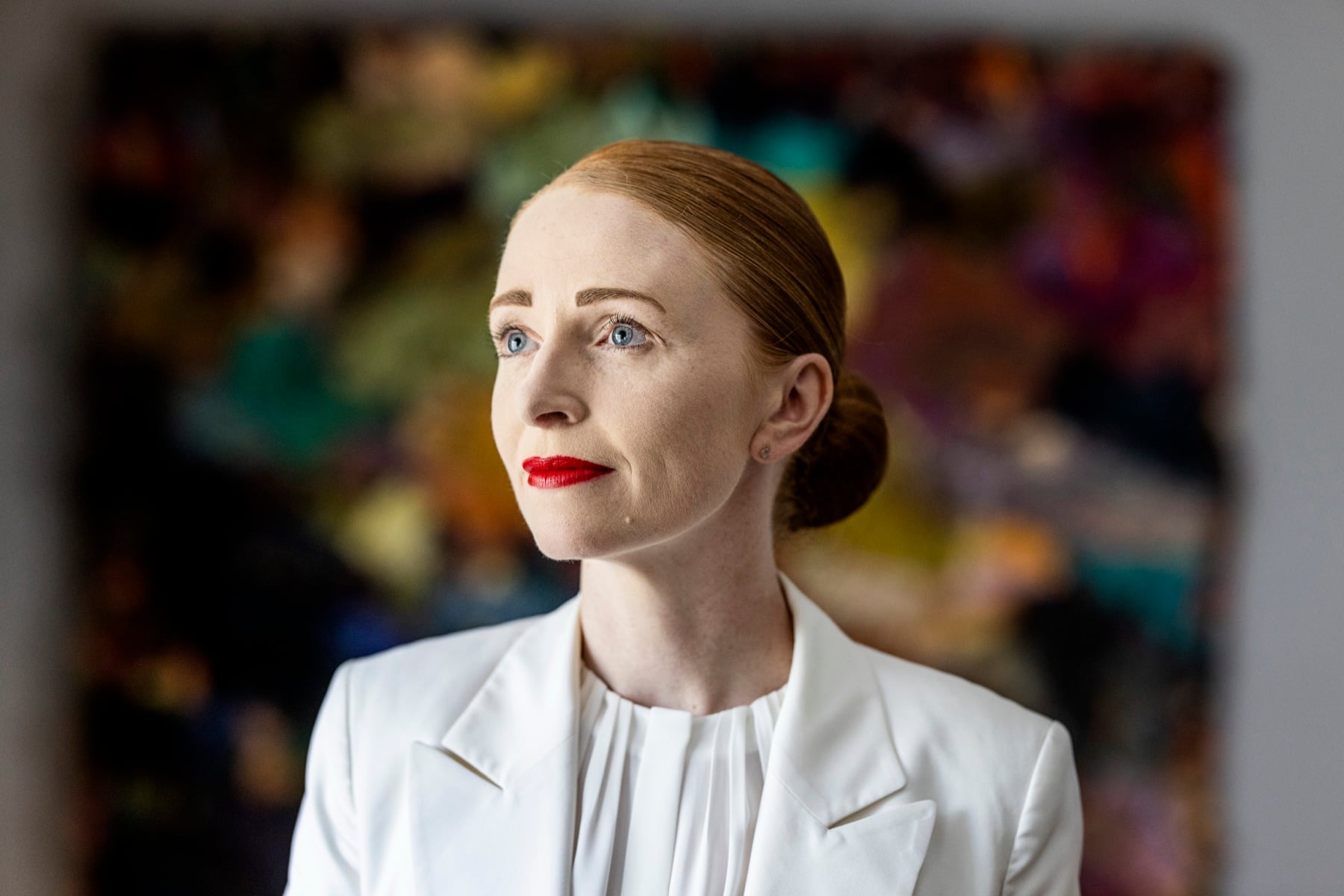 Tina Kragh Vildgaard im weißen Blazer vor einem farbigen Gemälde