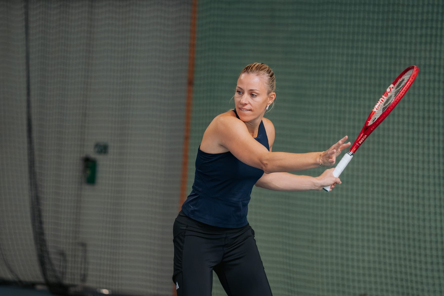 Angelique Kerber in dunkelblauem Top schlägt in einer Tennishalle eine Vorhand mit rotem Schläger