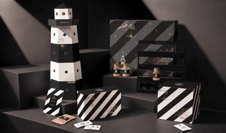 Vier Ankerkraut-Adventskalender in Schwarz-Weiß, darunter einer in Leuchtturmform, mit Gewürzgläsern auf dunklen Podesten