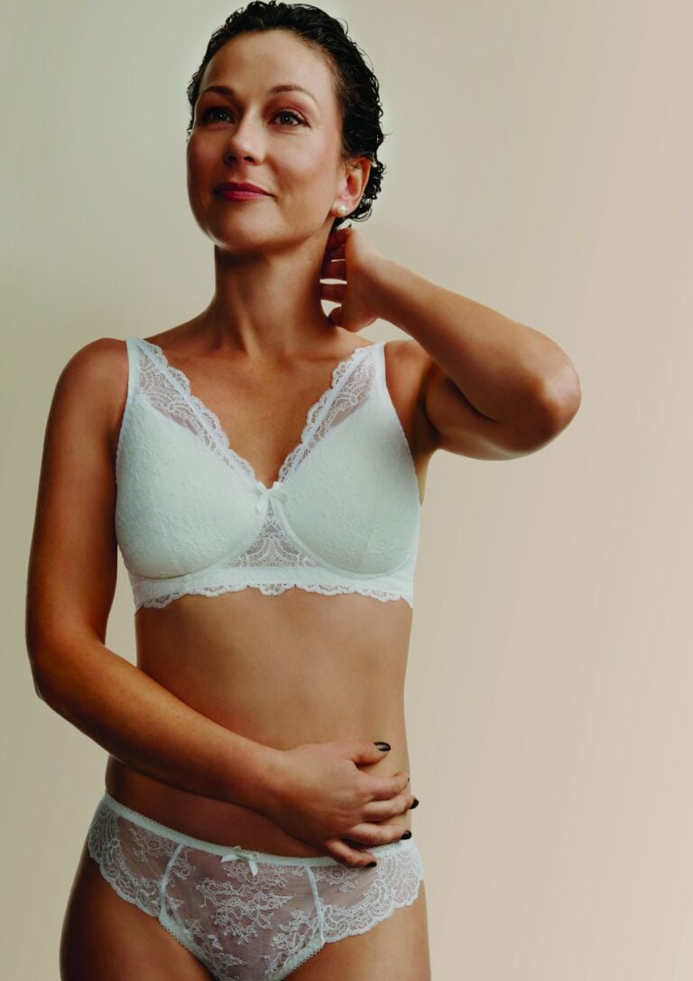 Frau in hellem Spitzen-BH und Slip aus der postoperativen Lingerie-Linie von Aubade