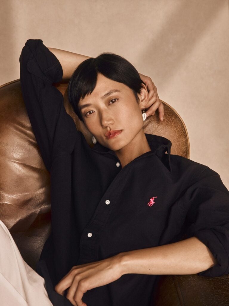 Person mit kurzem dunklem Haar im schwarzen Hemd mit pinkem Polo-Pony-Logo