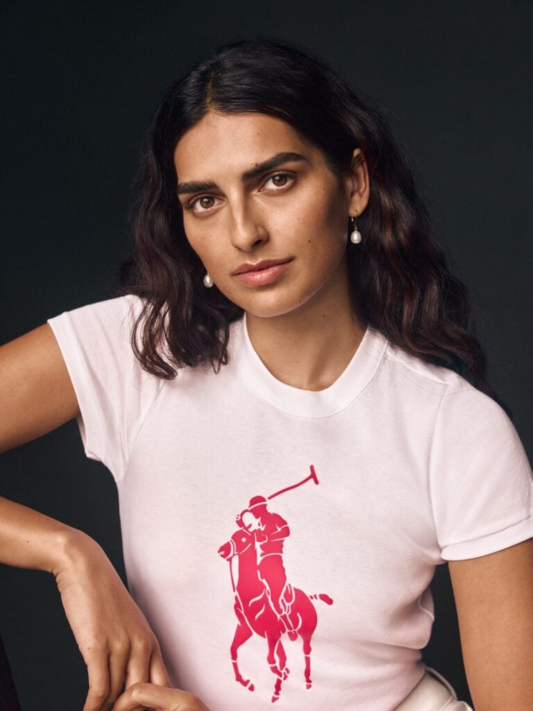 Frau mit dunklen Locken im rosa T-Shirt mit großem pinkem Polo-Pony-Logo