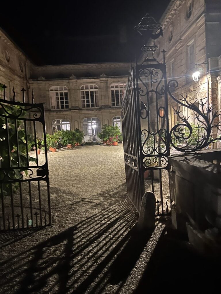 Innenhof des Châteaus bei Nacht mit schmiedeeisernem Tor