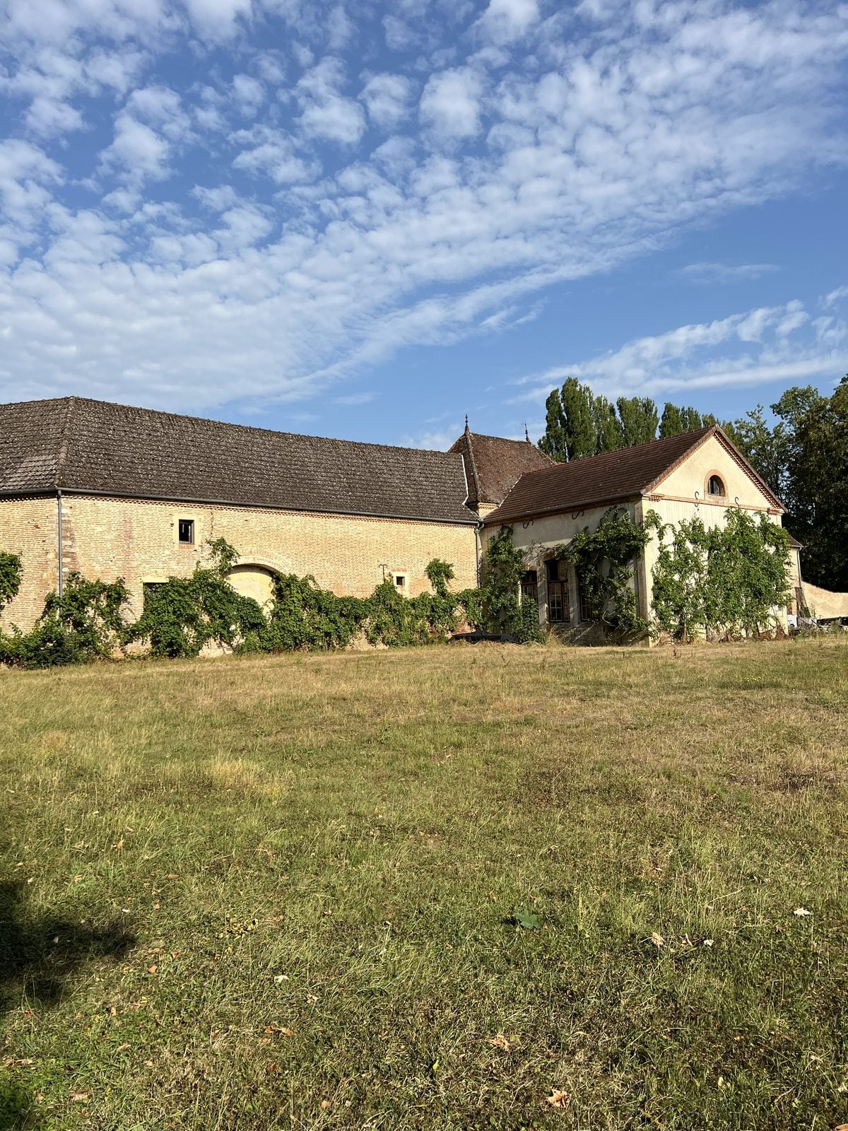 Nebengebäude des Châteaus hinter einer Wiese