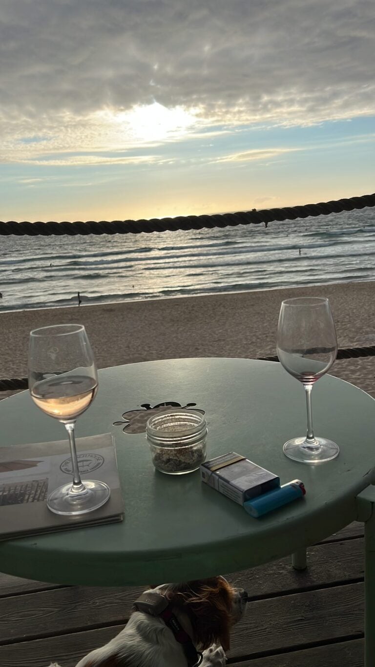 Zwei Weingläser auf einem Tisch mit Blick aufs Meer bei Sonnenuntergang