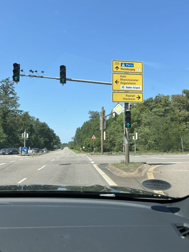 Ampelkreuzung mit Wegweisern, Blick durch die Windschutzscheibe