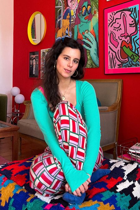 Porträt von Kimiya Justus in ihrer Wohnung mit ihren Werken im Hintergrund.